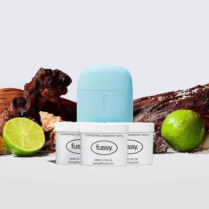 Fussy's All At Sea Scent Deodorant Pack featuring a Blue case and three refill packs set against a backdrop of cedarwood, limes and sea shells.