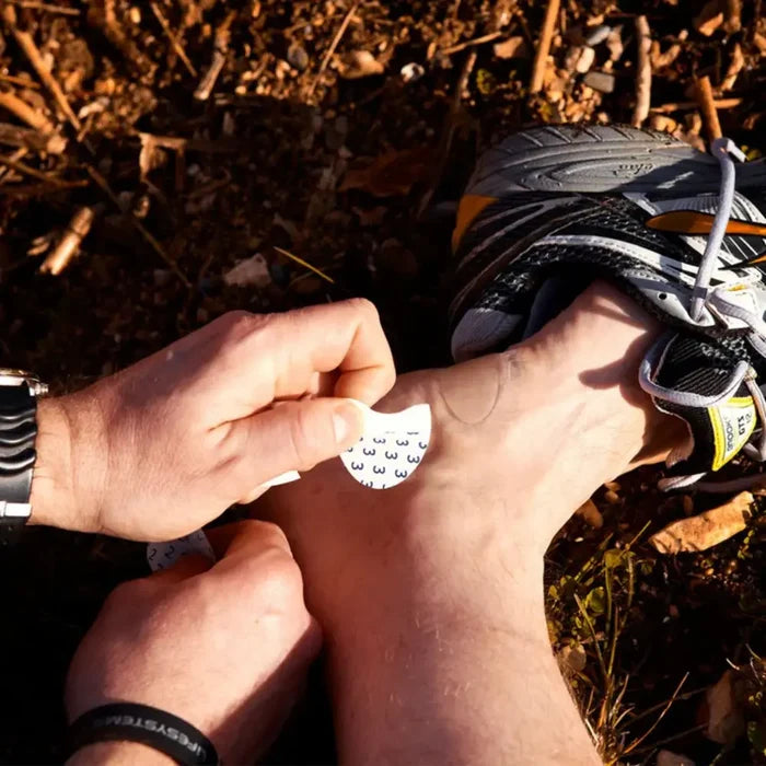 Walker applying a blister plaster from the first aid kit to the sole of their foot outdoors