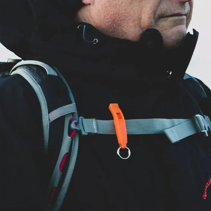 Lifesystems Echo tough plastic survival whistle in orange colour attached to a persons rucksack chest strap