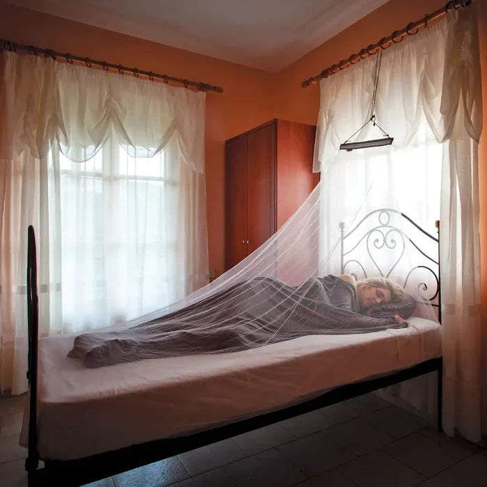 Women sleeping on a single bed under a Lifesystems Micro Single Mosquito Net