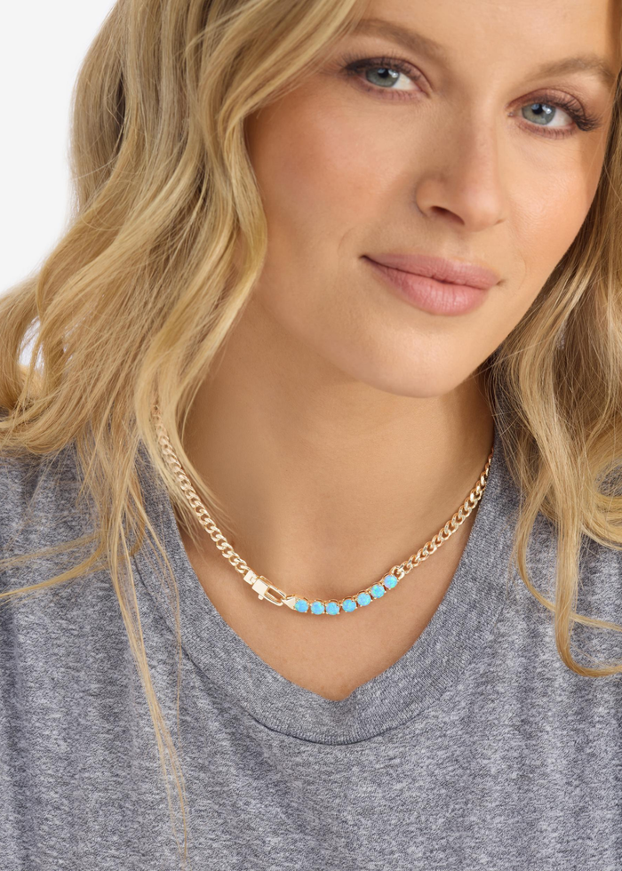 Woman wearing a gold chain necklace with seven blue opal stones
