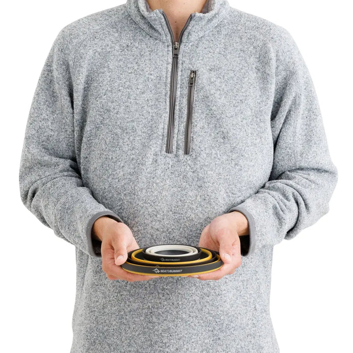 Man holding a nestled Sea To Summit 3 piece Frontier collapsible dinnerware set to show the relative size