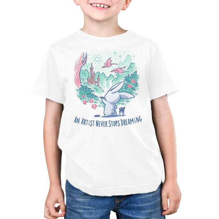 Premium Cotton T-shirt_TeeTurtle white An Artist Never Stops Dreaming apparel  featuring a bunny drawing a whimsical landscape with a castle, trees, and flying dragons. Caption reads, "an artist never stops dreaming".
