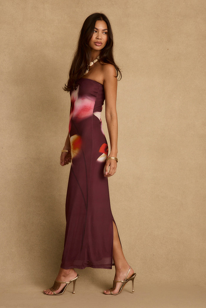 Side profile of the strapless Avani plum floral maxi dress, side slit and gold heels.