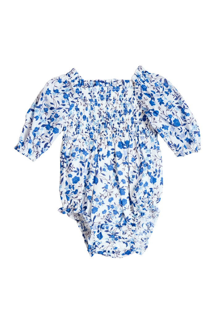 The Ivy City Co Baby Madeline Romper in Ditsy Cobalt Floral has long sleeves, a white background, smocked chest, and elastic leg openings—perfect for matching with Mom for adorable moments.