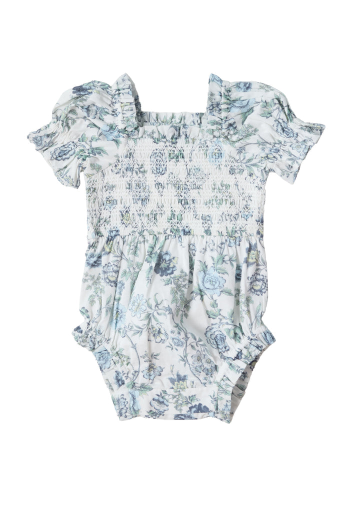 The Ivy City Co Baby Valencia Romper in Ivory Climbing Vine Bloom is a cotton baby romper with short puff sleeves, a smocked bodice, ruffled edges, and a blue floral print, shown laid flat on a white background.