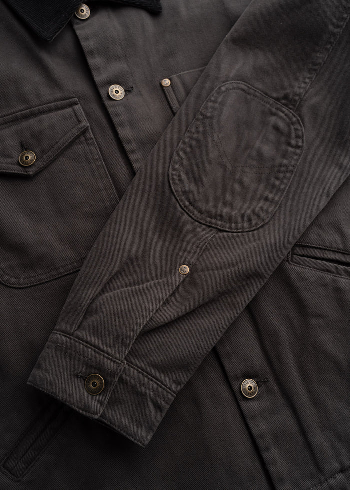 Close up of peach bull denim fabric showing, custom buttons, detailed stitching, custom buttons, textured cotton weave and durable workwear construction