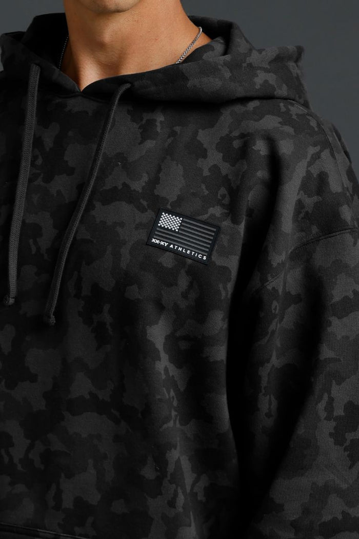 Black camouflage hoodie with a patch on a dark background || Black Camo