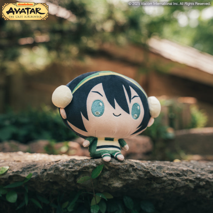 Cloudheads: 5" Toph sitting on a flat rock with a garden in the background