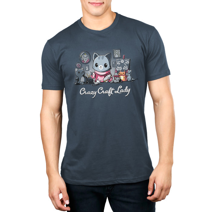 Premium Cotton T-shirt_TeeTurtle denim blue Crazy Craft Lady apparel featuring a cat happily sewing, surrounded by cat themed craft projects. Caption reads, "crazy craft lady".