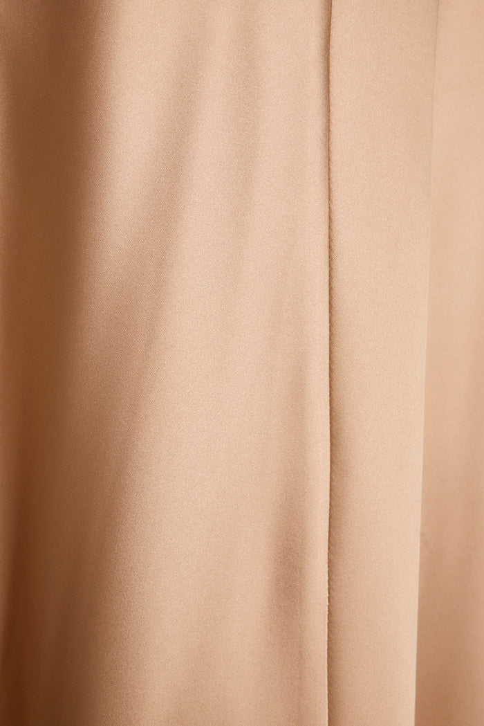 Close-up of champagne satin fabric showing the seam and soft sheen of the maxi dress.