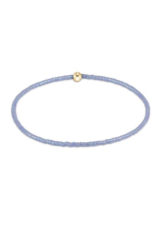 Light blue beaded bracelet with one gold bead on a white background
