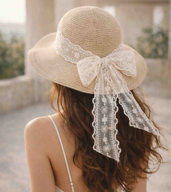 Beige straw wide-brim sun hat with white lace ribbon and bow at back