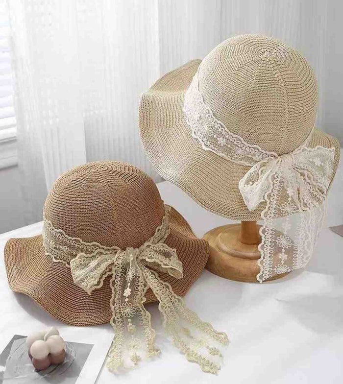 Two straw sun hats, beige and brown, with white lace ribbon and bows