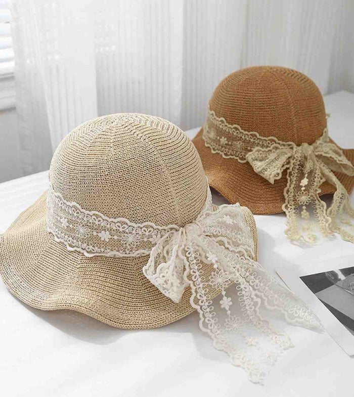 Beige straw sun hat with white lace ribbon and bow, side view