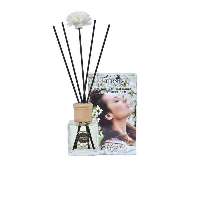 Reed diffuser bottle with dark rattan reeds and white flower topper in wooden sleeve