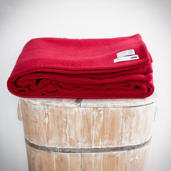 Folded cherry colour king wool blanket with co-ordinated stitch.