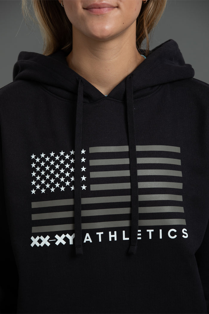 Black hoodie with American flag design and 'XXXY Athletics' text on a dark background || Black