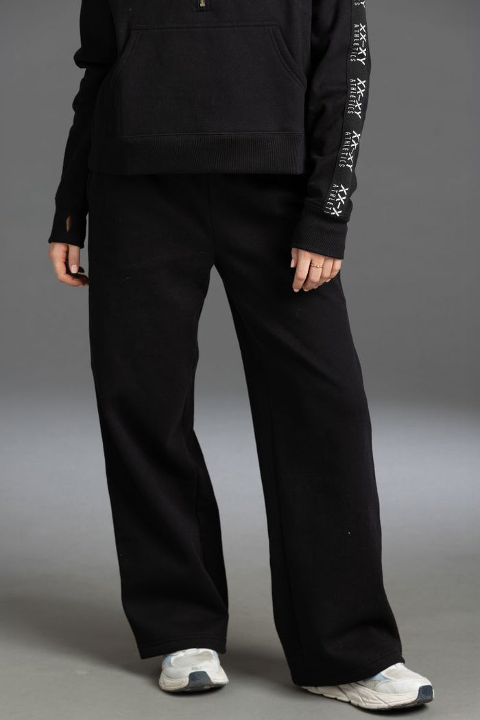 Person wearing a black outfit with wide-leg pants on a gray background || BLACK
