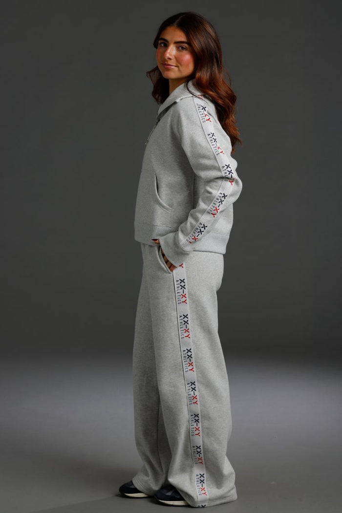 Woman wearing a gray tracksuit with embroidered details on a dark background || Light Heather Gray