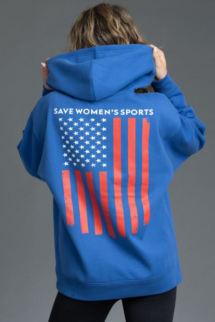 Person wearing a blue hoodie with an American flag and 'Save Women's Sports' text || Blue