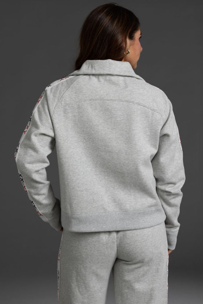 Person wearing a gray tracksuit with floral embroidery on sleeves || Light Heather Gray