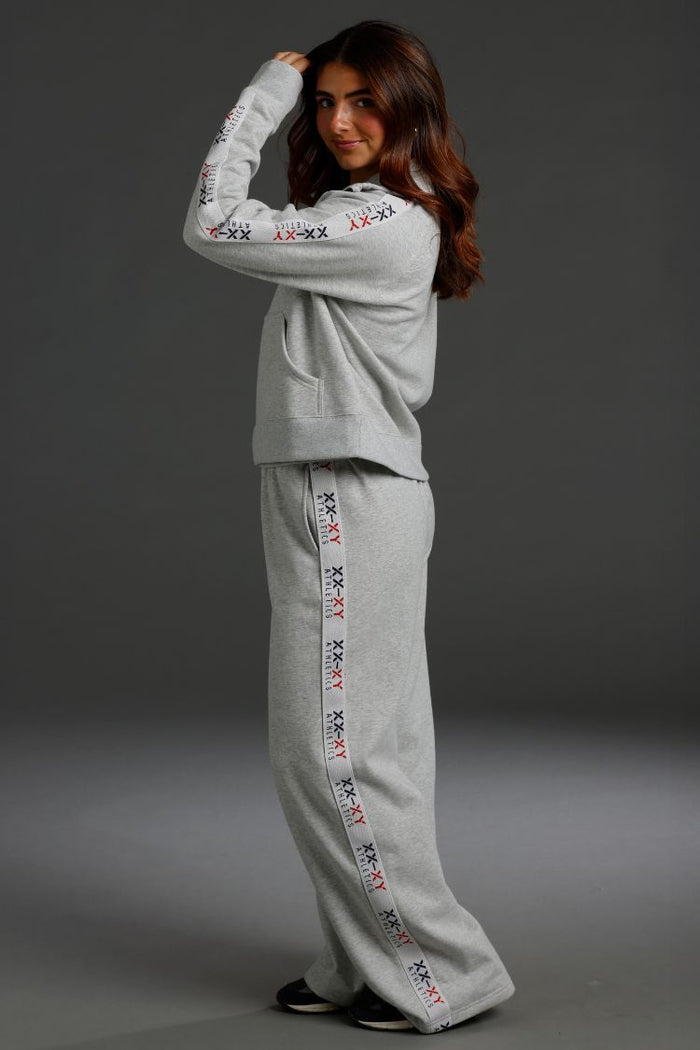 Woman wearing a gray tracksuit with embroidered details on a dark background || Light Heather Gray