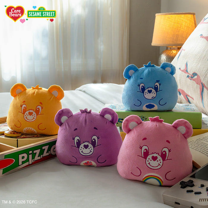 Cheer Bear & Elmo 4" Reversible Plushie, Grumpy Bear & Oscar 4" Reversible Plushie, Share Bear & Cookie Monster 4" Reversible Plushie, Funshine Bear & Big Bird 4" Reversible Plushie sitting on a bed surrounded by toys and books