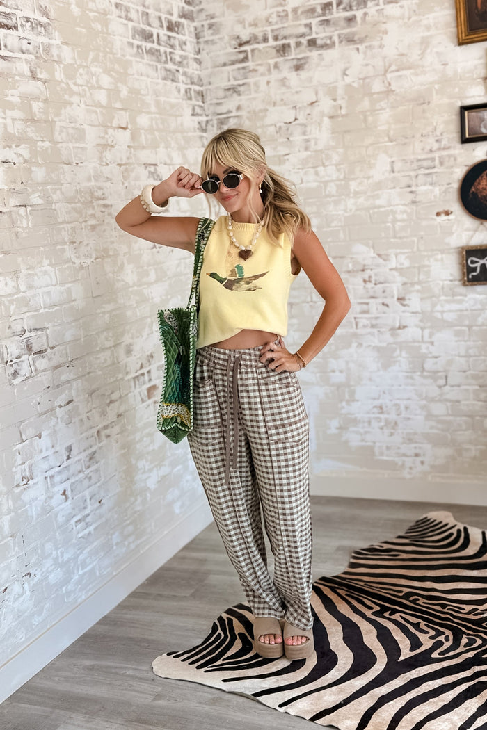 Woman wearing soft brushed mocha check barrel-leg utility pants with oversized patch pockets, exposed seam detailing, elastic drawstring waistband, and a relaxed ankle-length fit.