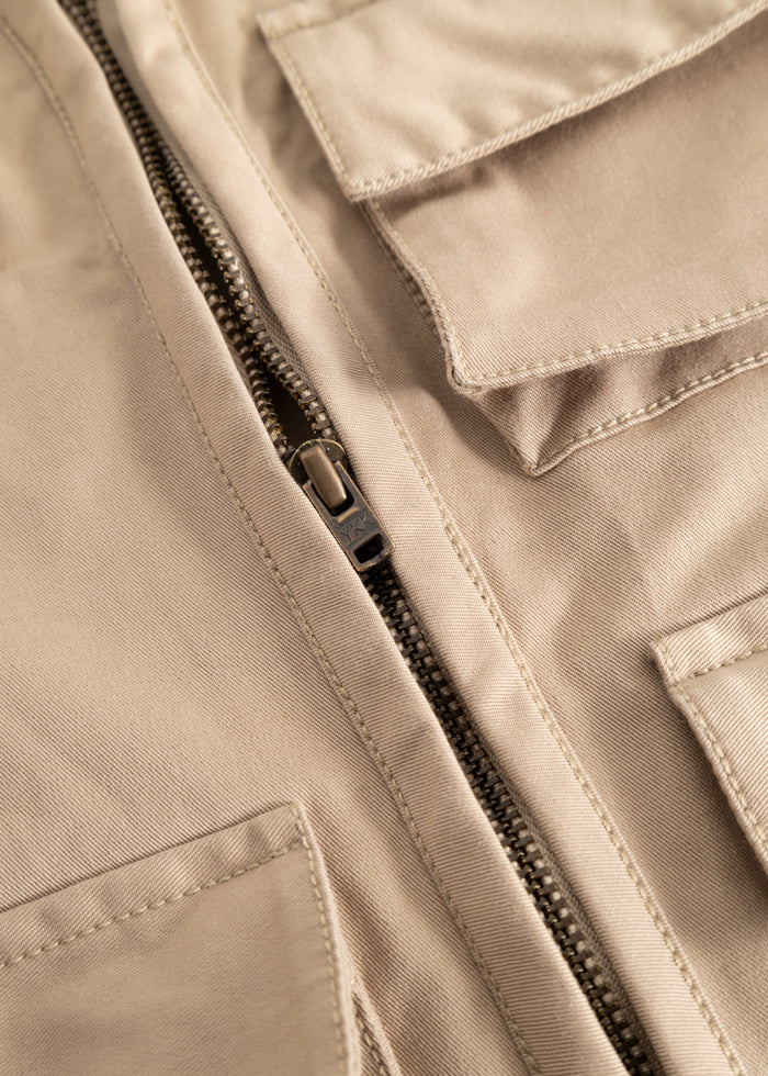 Sand-colored children's vest with a strong black zipper and visible seams.