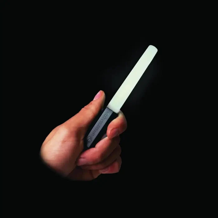Person holding a Lifesystems Intensity LED Glow Marker with it lit white, on a black background