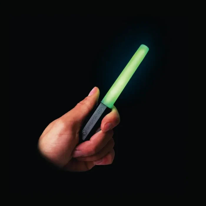 Person holding a Lifesystems Intensity LED Glow Marker with it lit green, on a black background