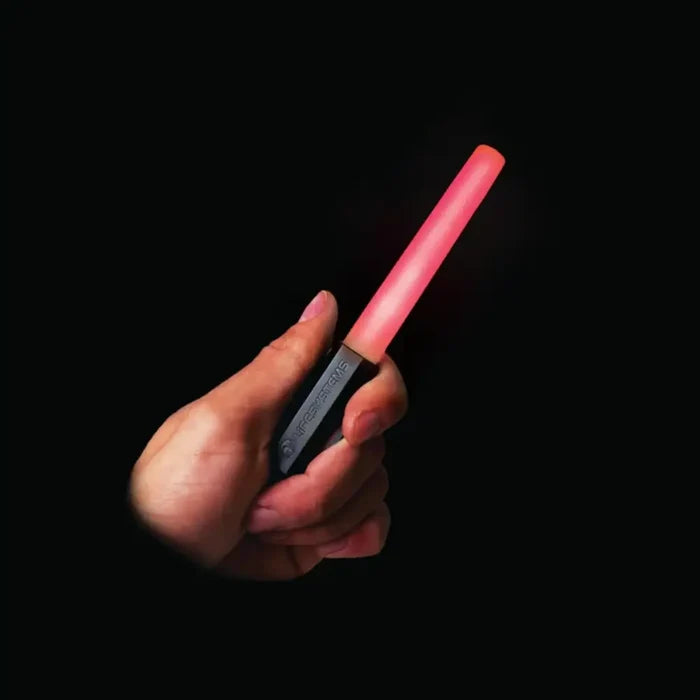 Person holding a Lifesystems Intensity LED Glow Marker with it lit red, on a black background