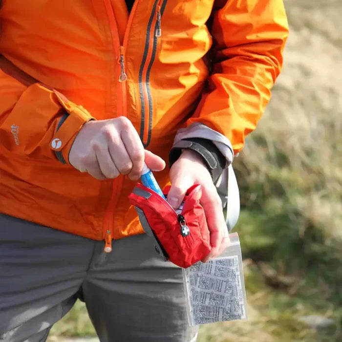 person taking some items ourt of a Lifesystems Pocket First Aid Kit whilst walking in the countryside