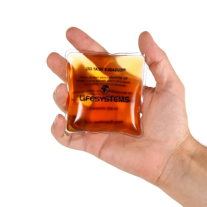 Hand holding a LifeSystems reusable hand warmer against a white background
