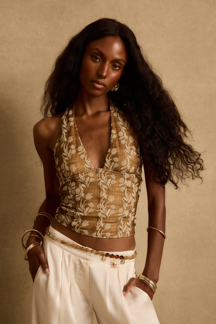 Mocha floral halter top with deep v neckline styled with cream trousers and gold bangles.