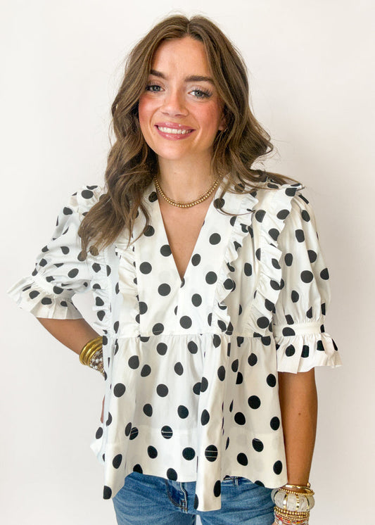 Woman wearing a polka dot blouse with a plain background