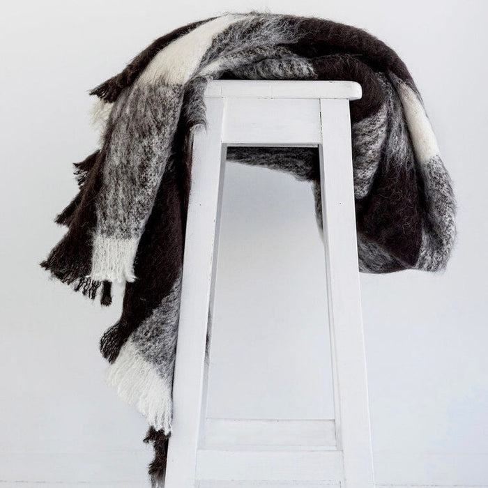 Alpaca fleece throw in Friesian colour draped on chair.