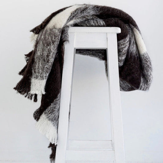 Alpaca fleece throw in Friesian colour draped on chair.