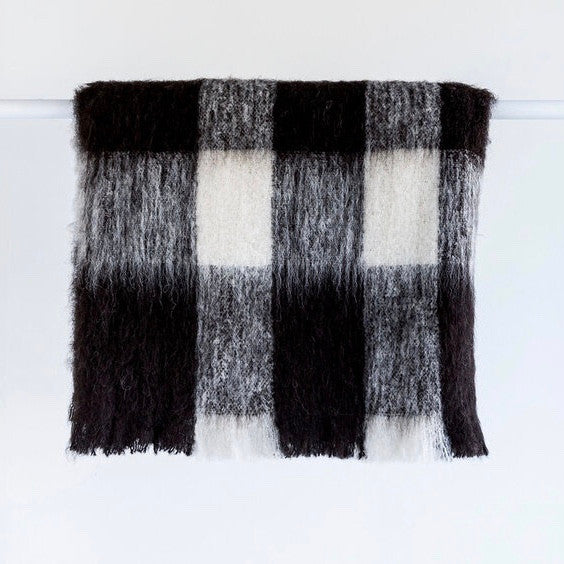 Alpaca fleece throw in Friesian colour folded on rack.