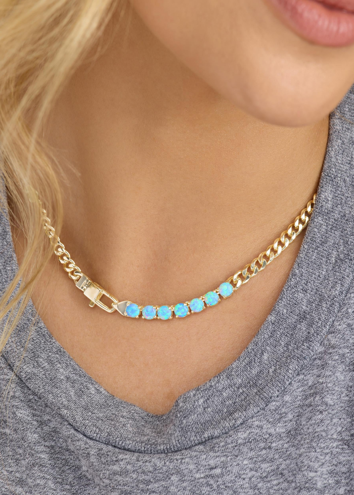 Woman wearing a gold chain necklace with seven blue opal stones