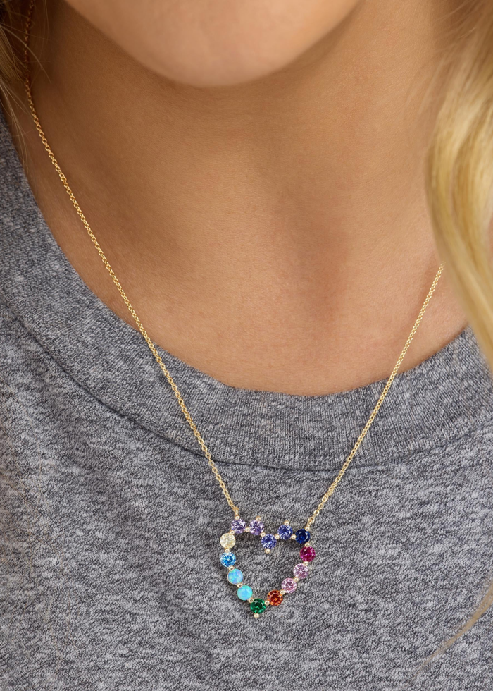 Woman wearing a gold chain necklace with a multicolor heart pendant