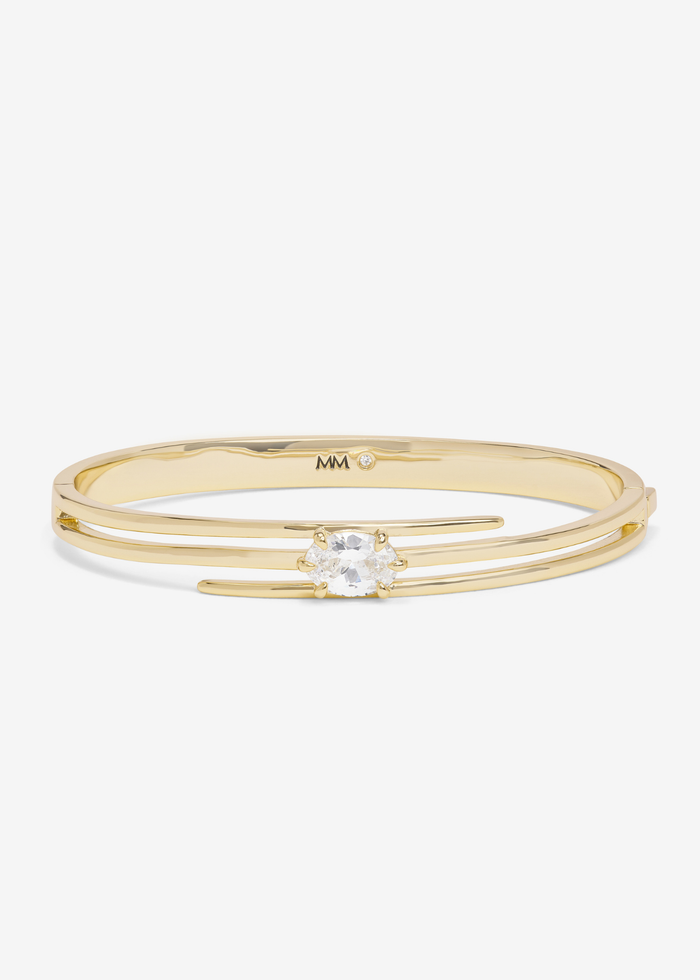 Gold lasso cuff bracelet with a diamond stud against a white background
