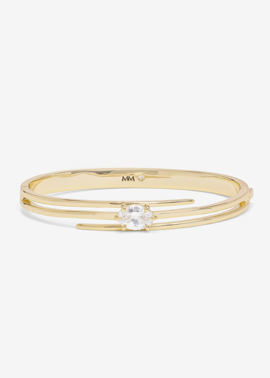 Gold lasso cuff bracelet with a diamond stud against a white background