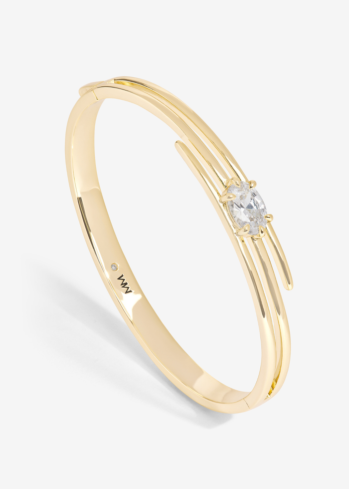 Gold lasso cuff bracelet with a diamond stud against a white background