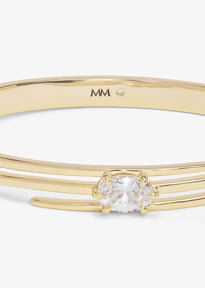 Gold lasso cuff bracelet with a diamond stud against a white background