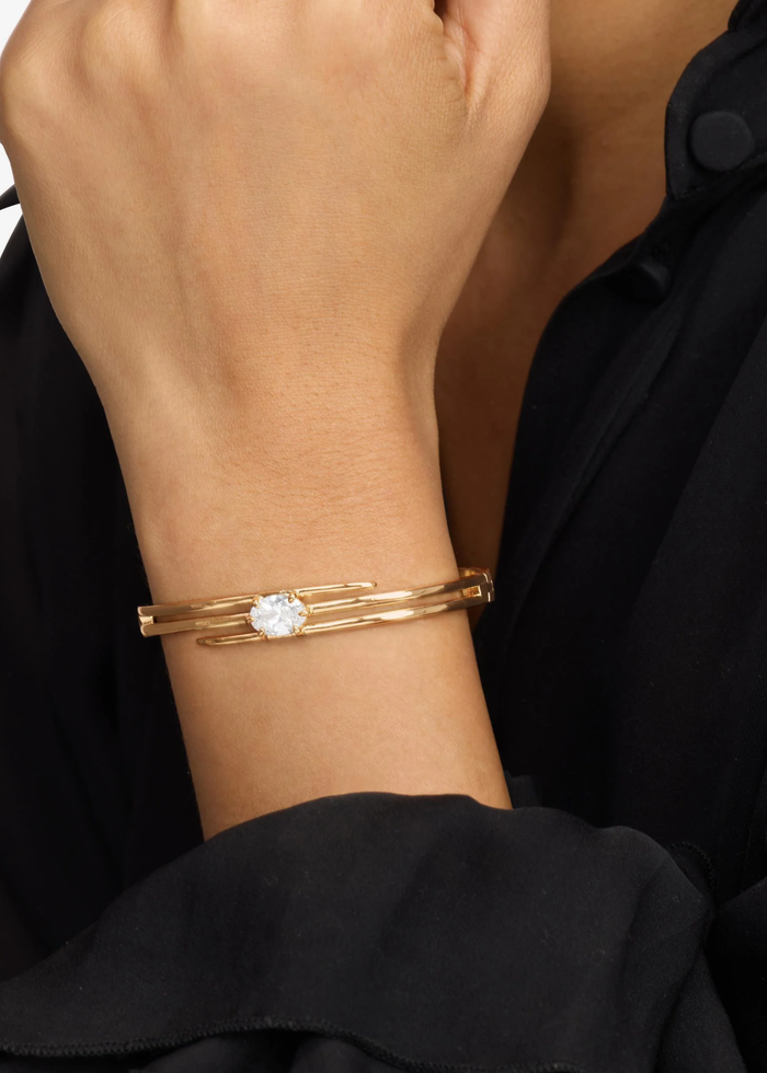 Woman wearing a gold lasso cuff bracelet with a diamond stud