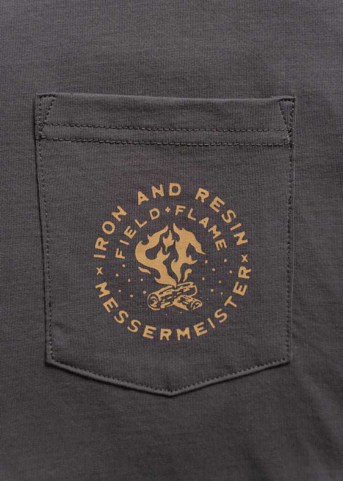 Gray shirt pocket with "Iron and Resin Field Flame Messermeister" logo in yellow, featuring a flame and log design.