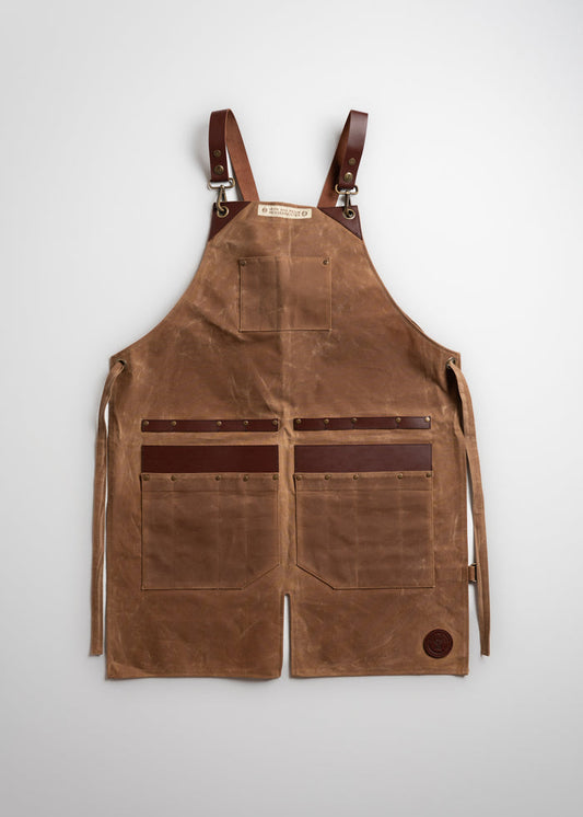 Brown leather apron with adjustable straps, multiple pockets, and a logo patch, laid flat on a white background.