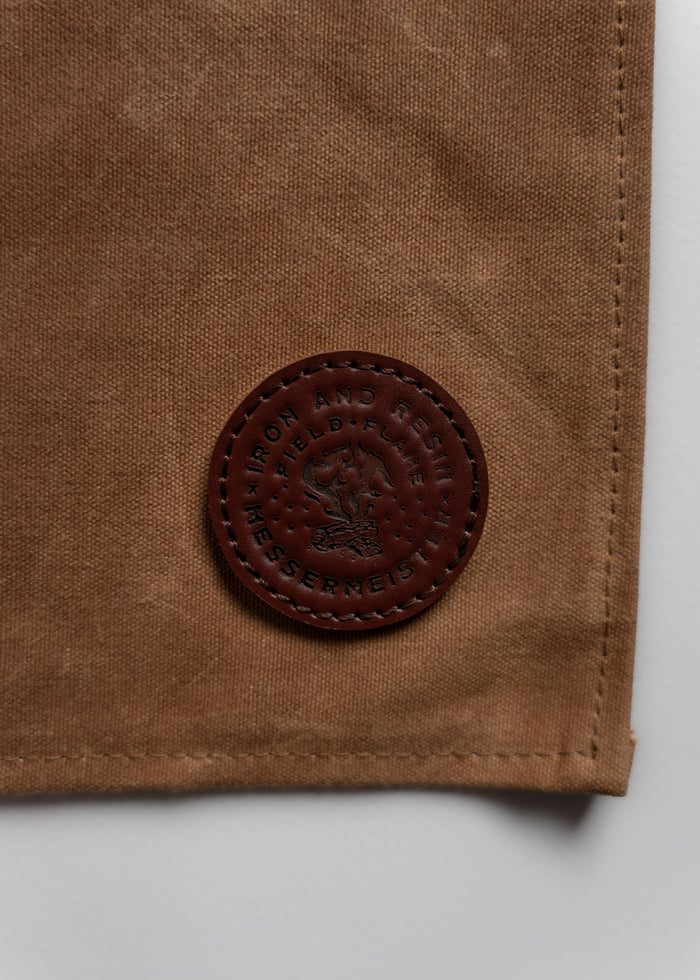 Brown fabric with a round, embossed leather patch labeled "Iron and Resin" and "Messermeister" in dark brown stitching.